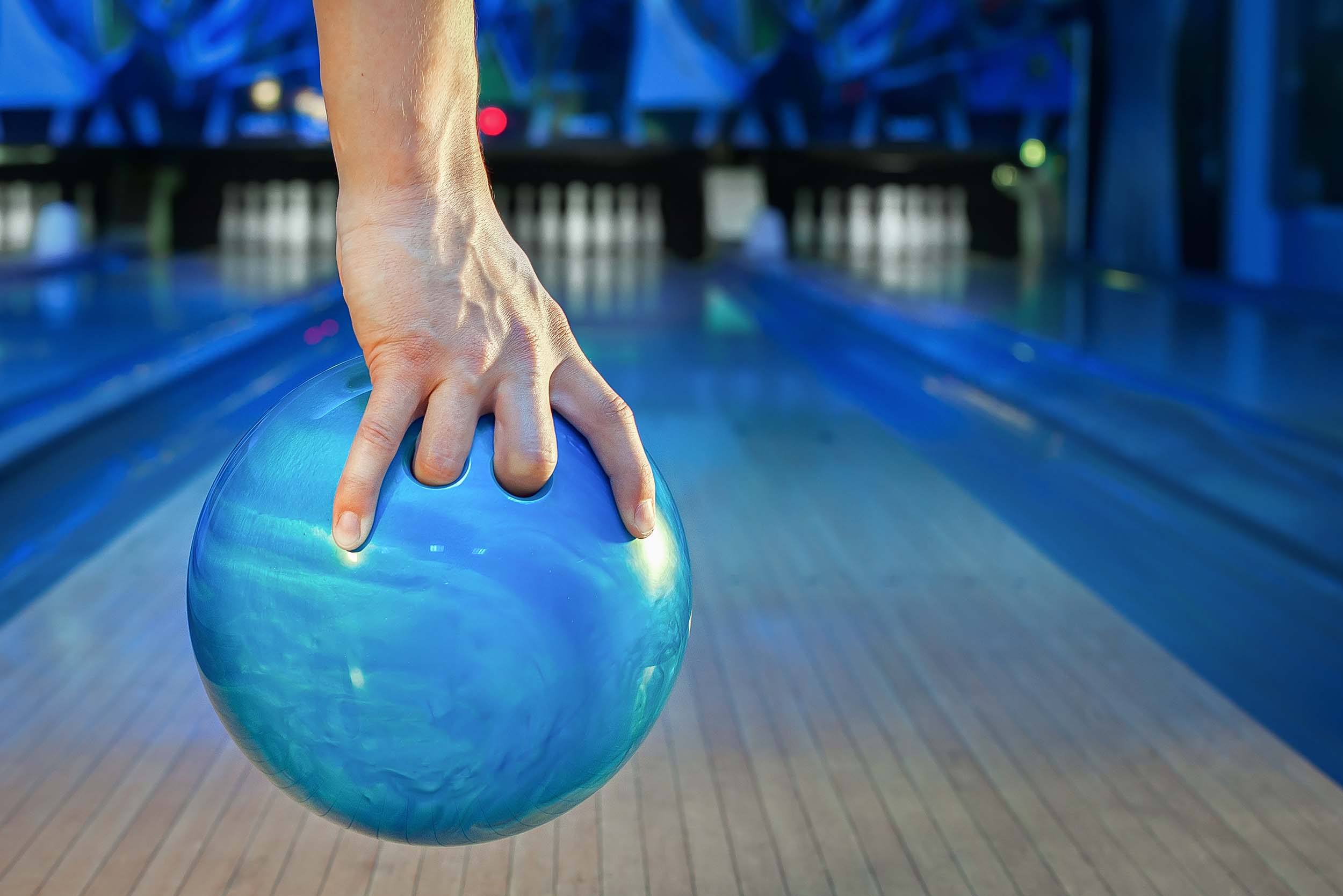main tenant une boule de bowling bleue