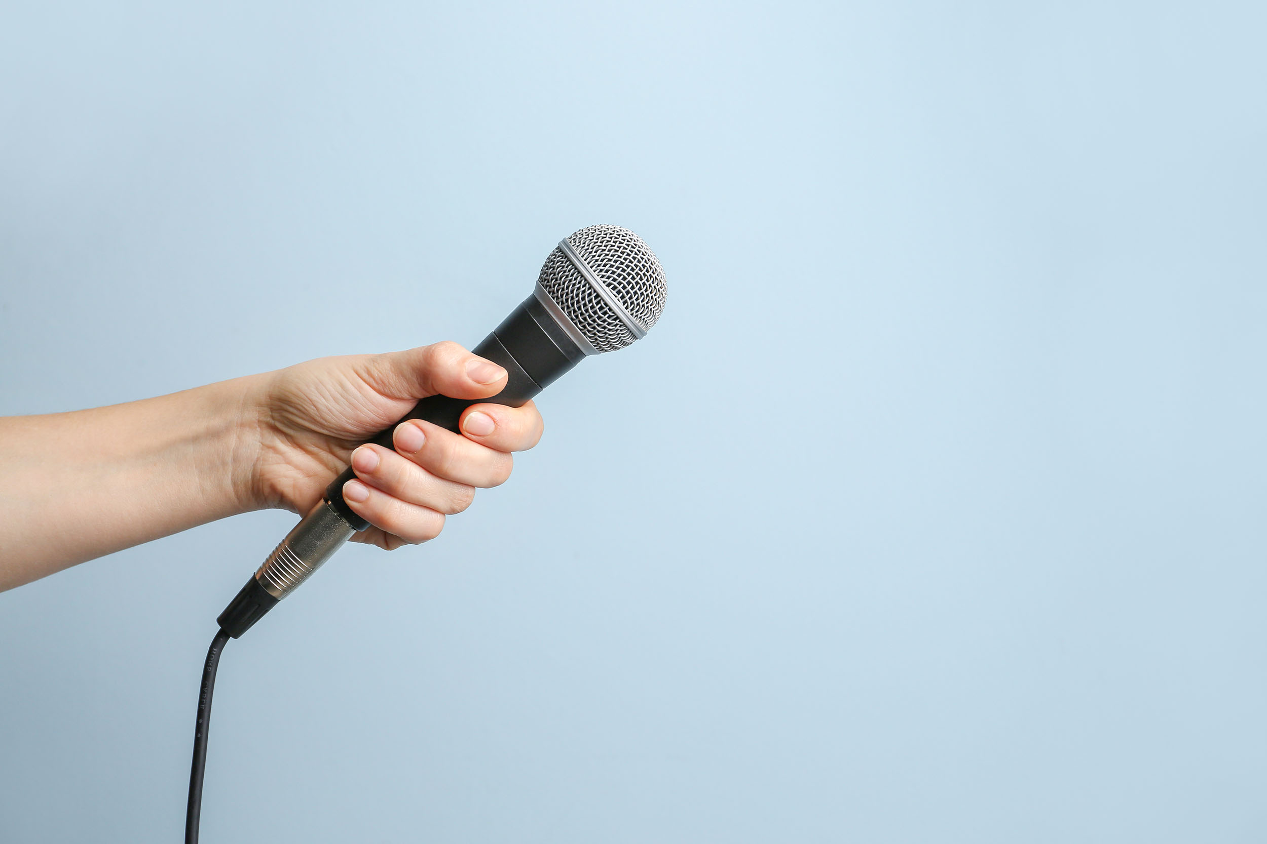 Hand holding a microphone on a blue background