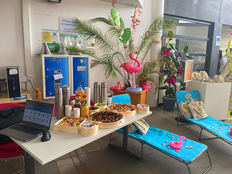 Une table avec des gateaux et des boissons ainsi qu'un ordinateur dans une BU