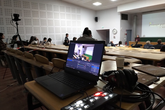 Ordinateur et caméra captant une conférence dans un amphithéâtre