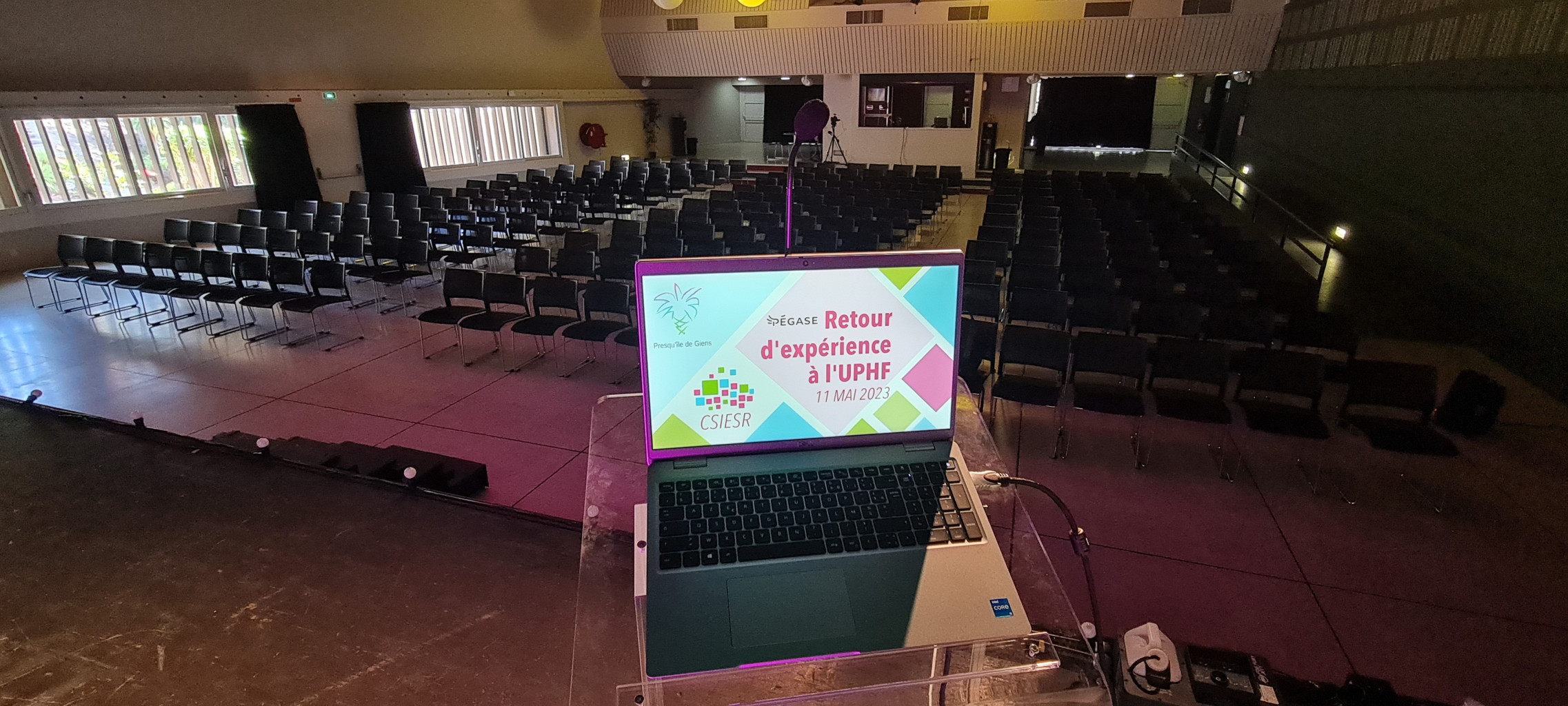 Computer displaying the conference presentation with the empty conference room in the background