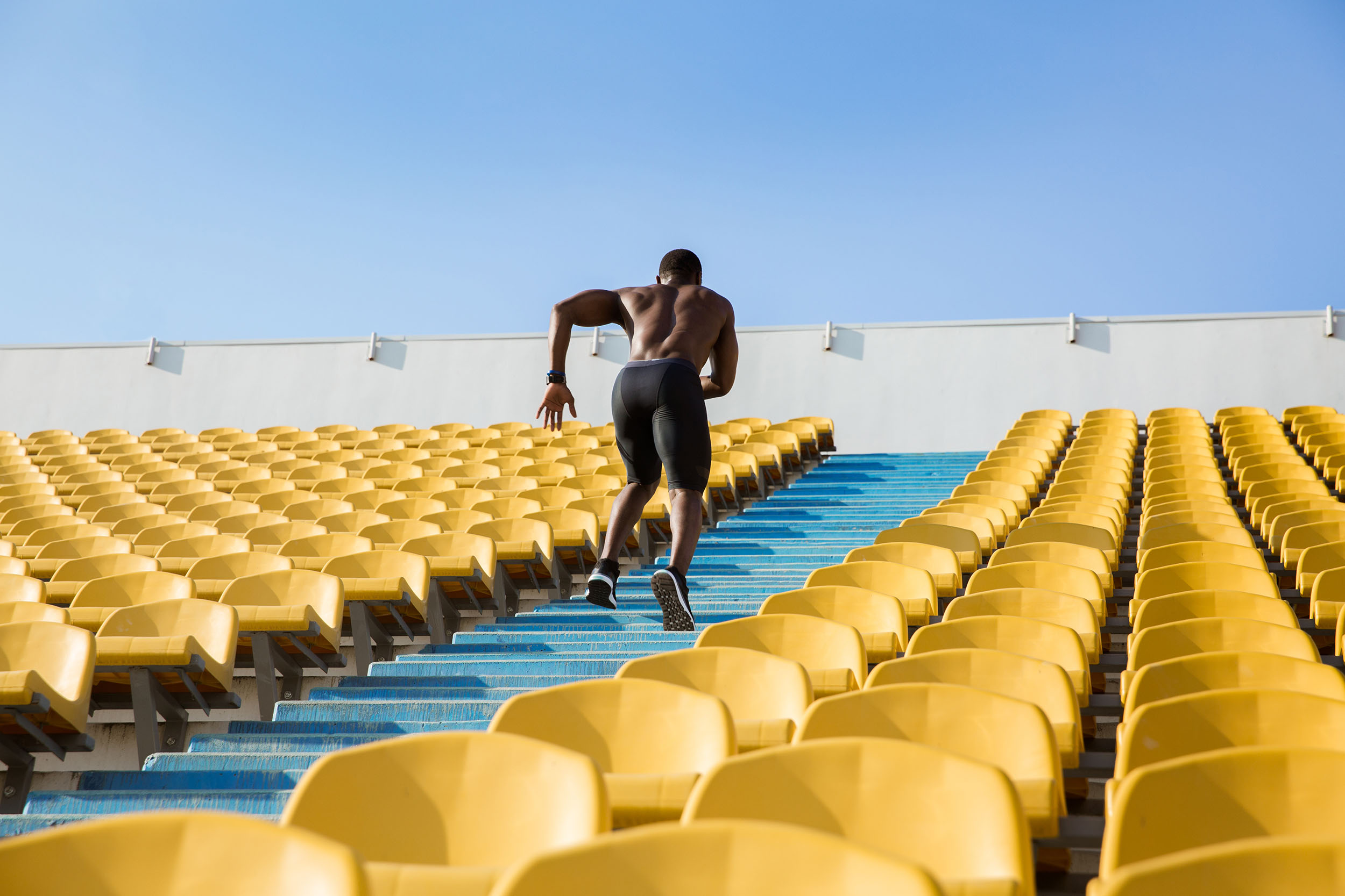 bare-chested runner coming up from the bleachers