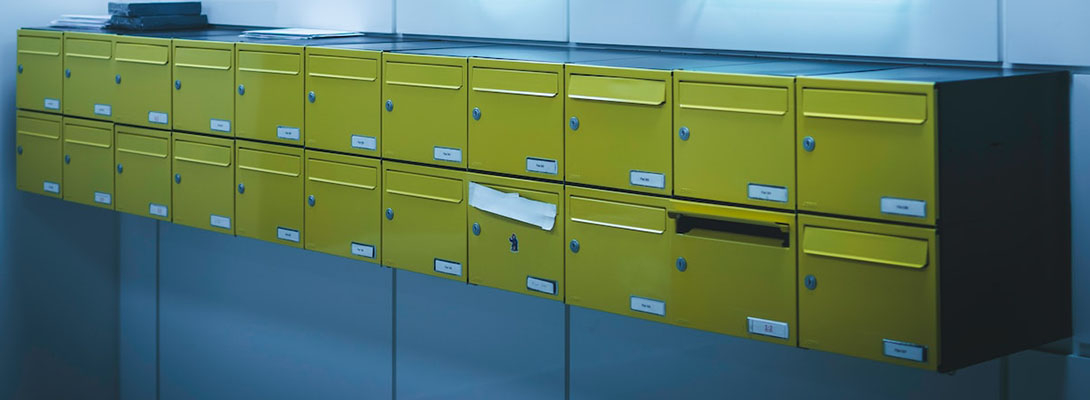 Two rows of yellow mailboxes on a blue wall