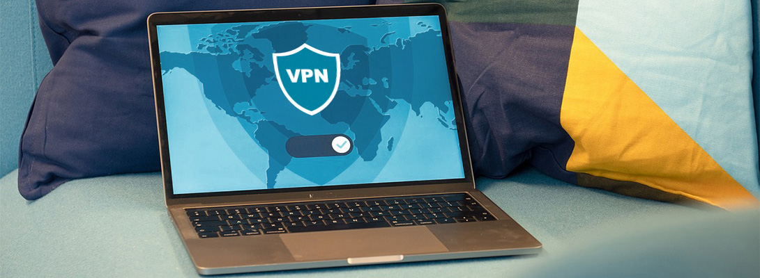 Ordinateur portable posé sur un sofa avec un logo VPN à l'écran